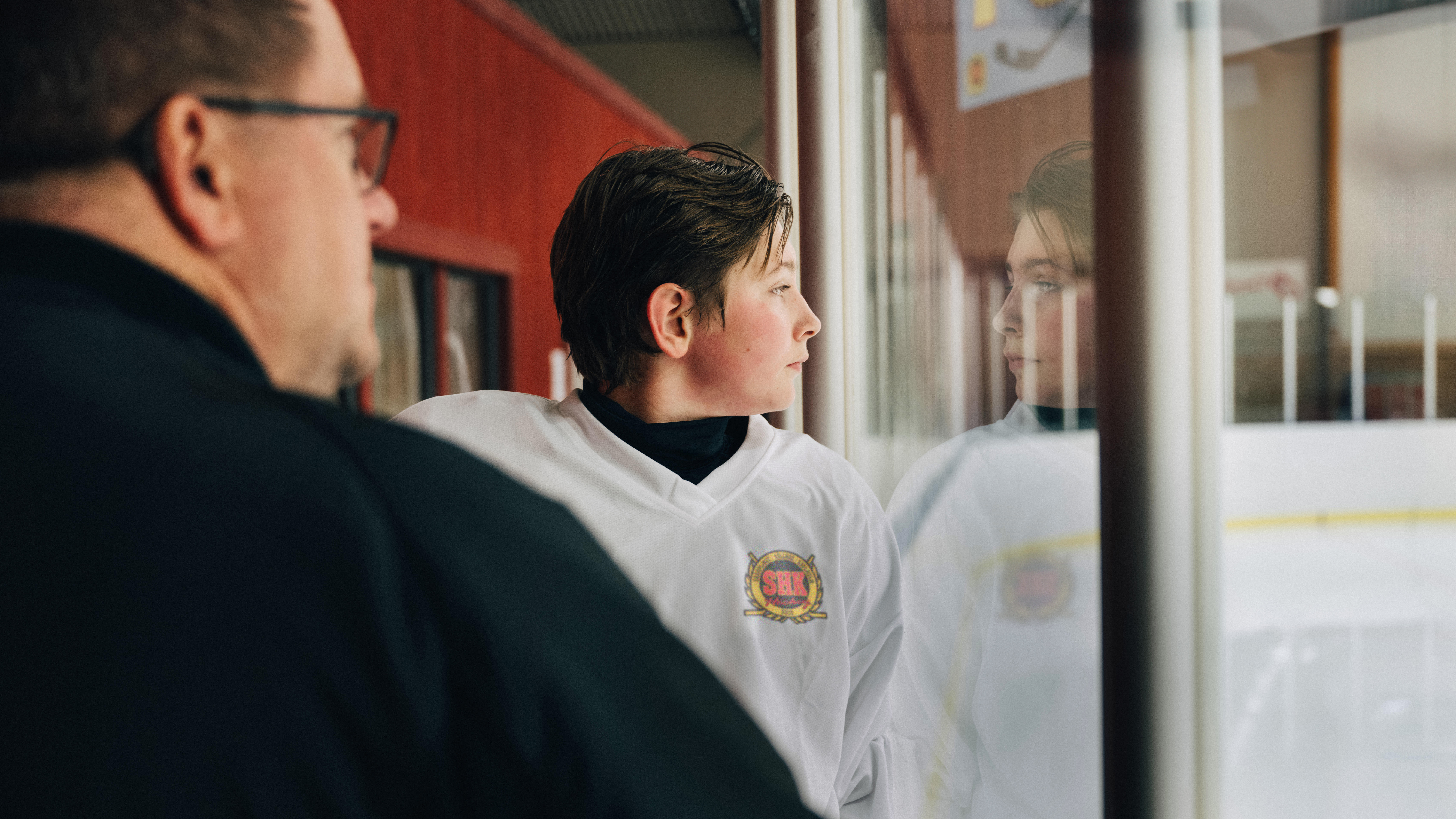 Pojke i hockeykläder bredvid tränare