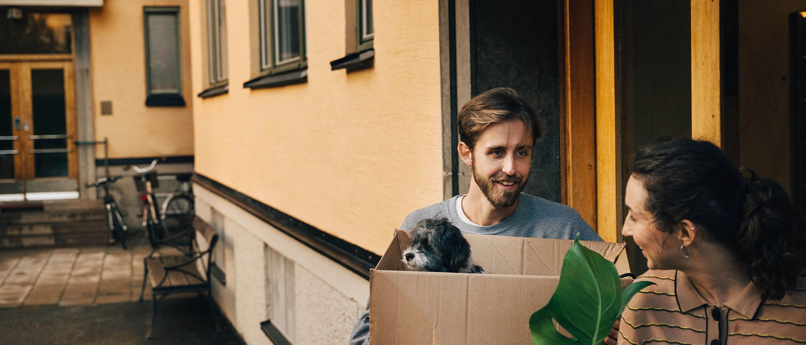 Par med flyttlådor och hund på väg in i port