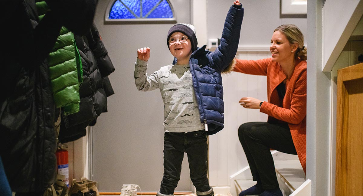 Mamma står i hallen och hjälper sitt barn klä på sig vinterjackan